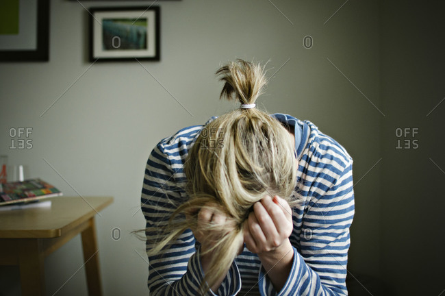 woman with messy hair holding her head in her hands