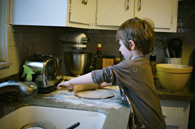 Boy rolling dough on kitchen counter