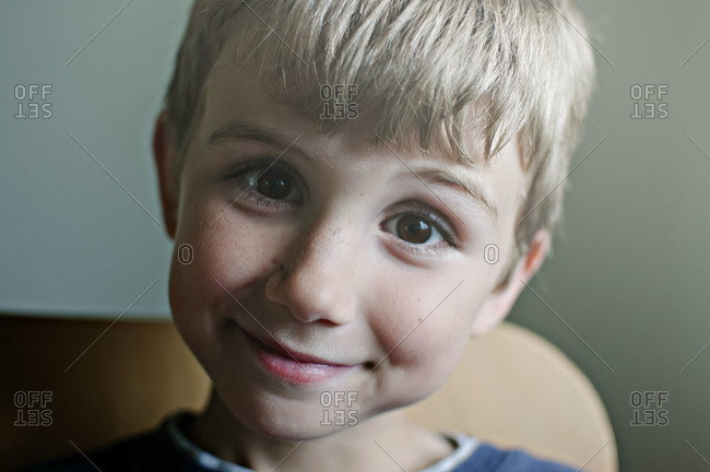 Close-up of boy with closed mouth smile and big brown eyes