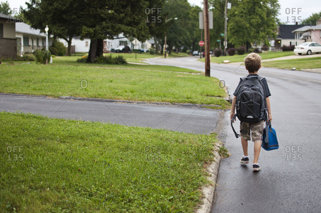 One boy walking to school with backpack and lunch bag.