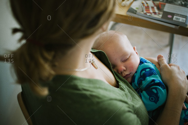 Mother is holding a sleeping baby.