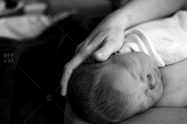 Newborn resting on Mom's chest while she holds his head.