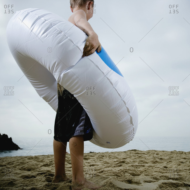 Young boy standing in an inflatable tube at the beach
