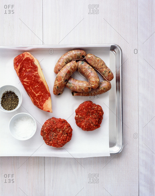 Raw beefsteak, sausages and burgers from above.