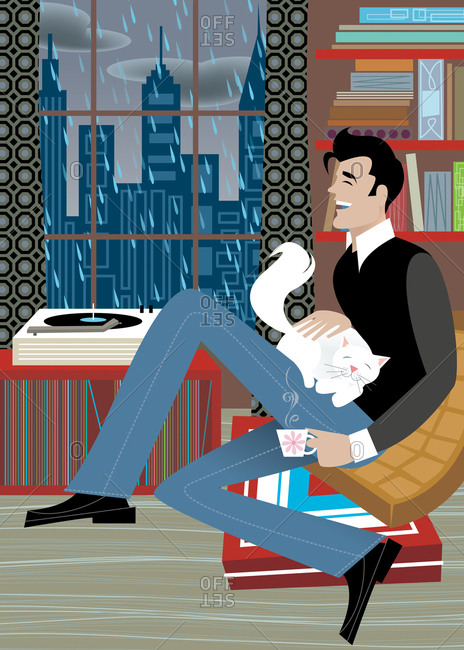 Handsome man sitting on floor pillows with cat and cup of tea and playing records on a rainy day