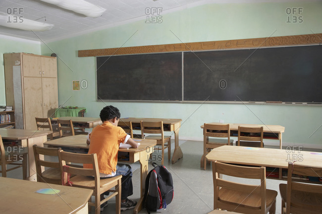 Mixed Race boy in empty classroom