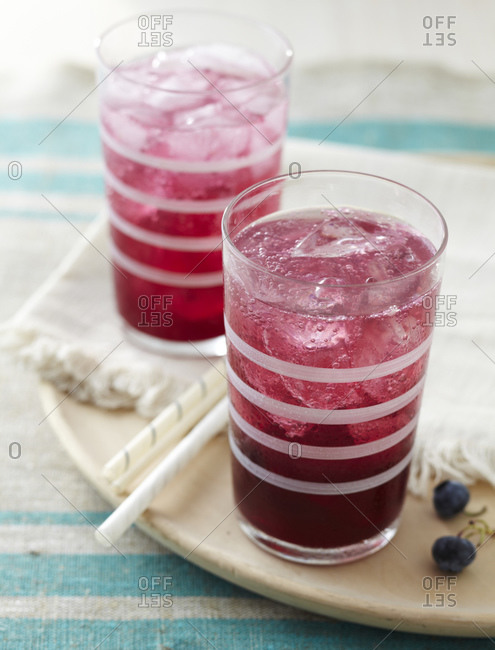 Blueberry syrup with sparkling water and ice cubes on a kitchen counter.