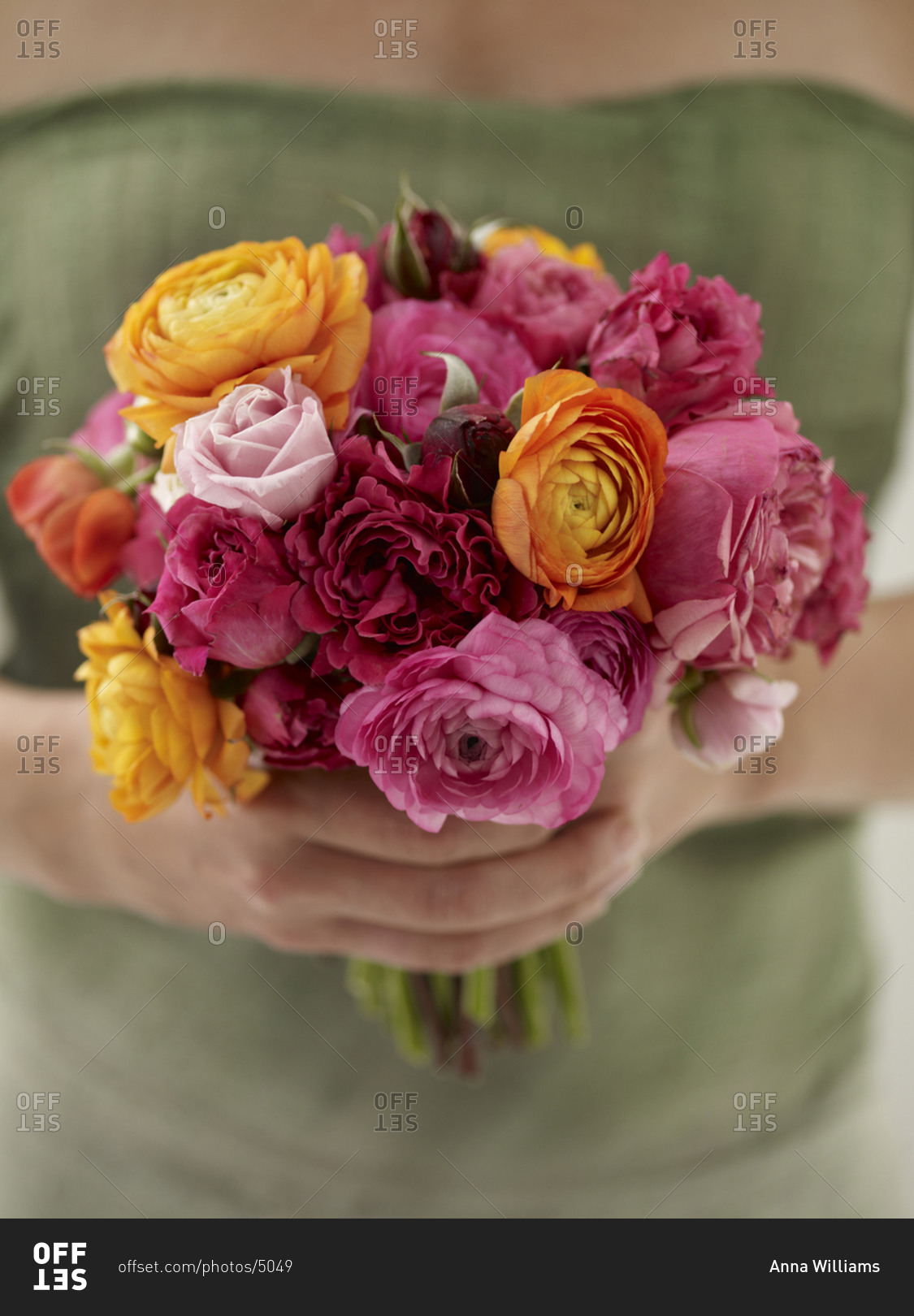 A woman holding a colorful cut flowers arranged into a bouquet.