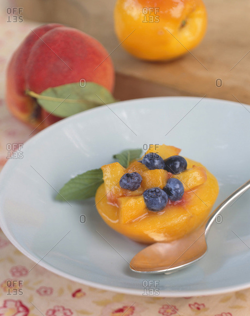 Halved fresh peach filled with raw blueberries and peach cubes.