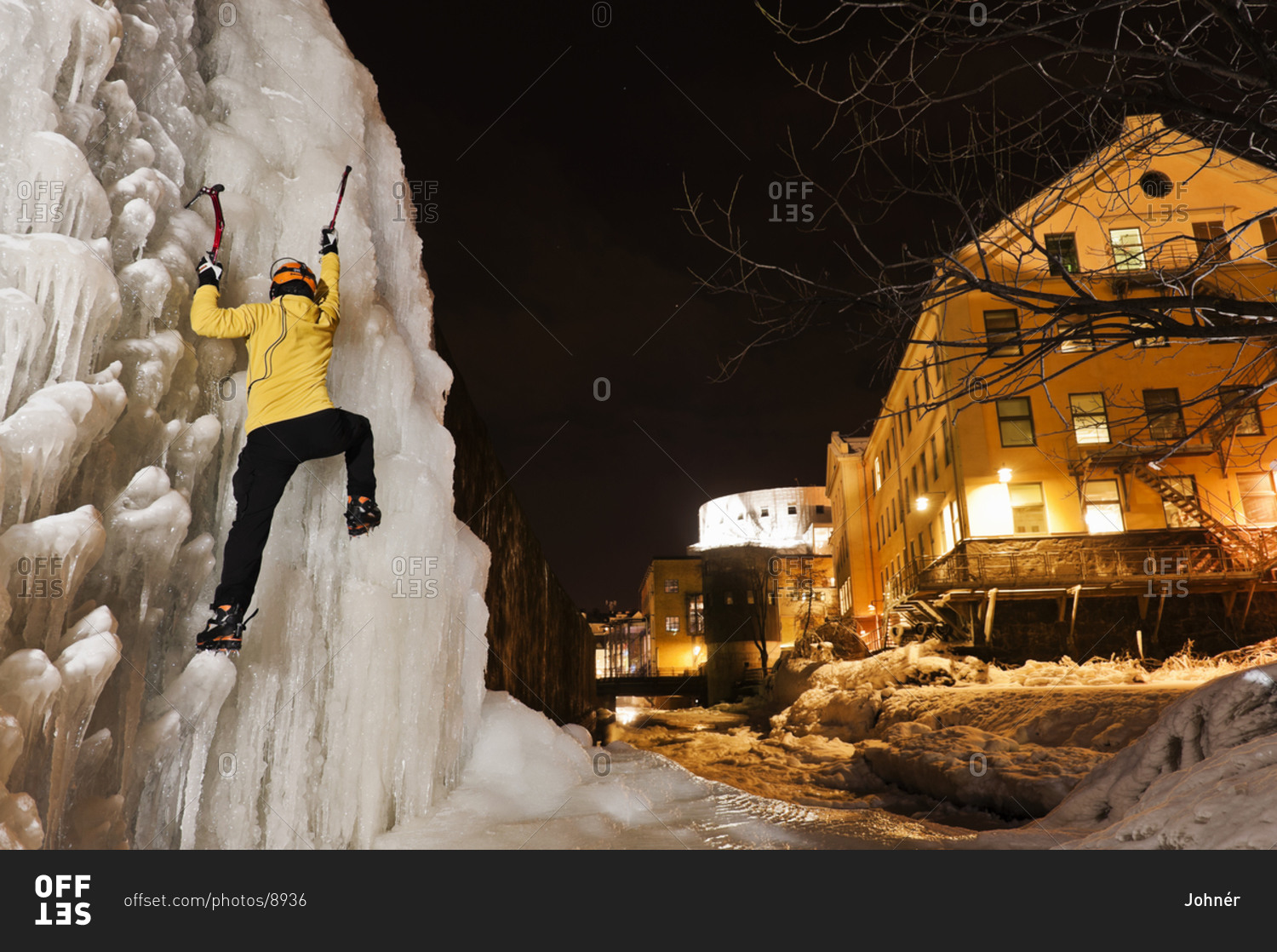 Man ice climbing up frozen waterfall in urban area adventure
