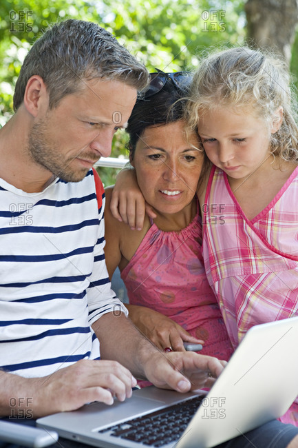 Parents with daughter using laptop in garden