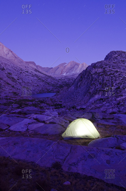 A tent is illuminated at dusk near Cirque Pass on the Sierra High Route, CA.