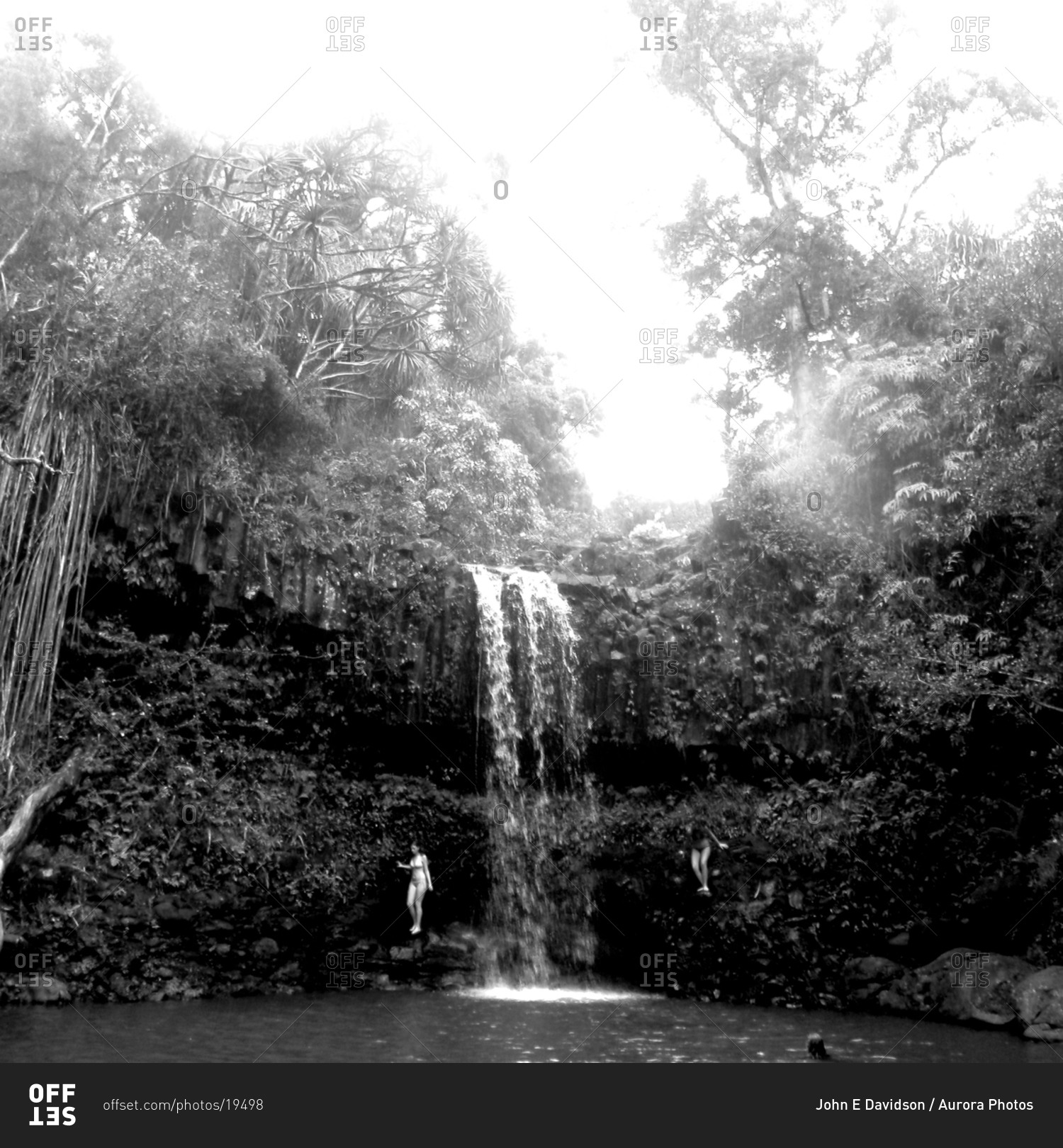 A black & white image of two girls swimming at a waterfall in Maui.