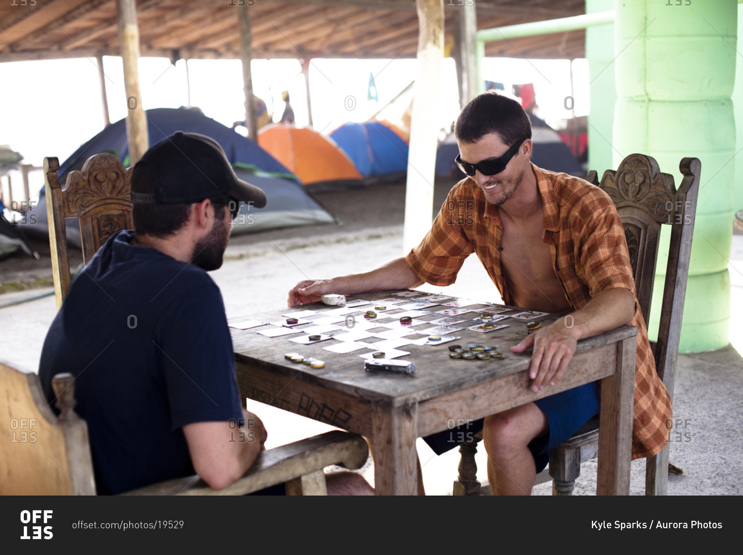 Two male surfers wearing sunglasses play a game of checkers by using playing cards and beer bottle caps during a surf trip to Pascuales, Mexico.