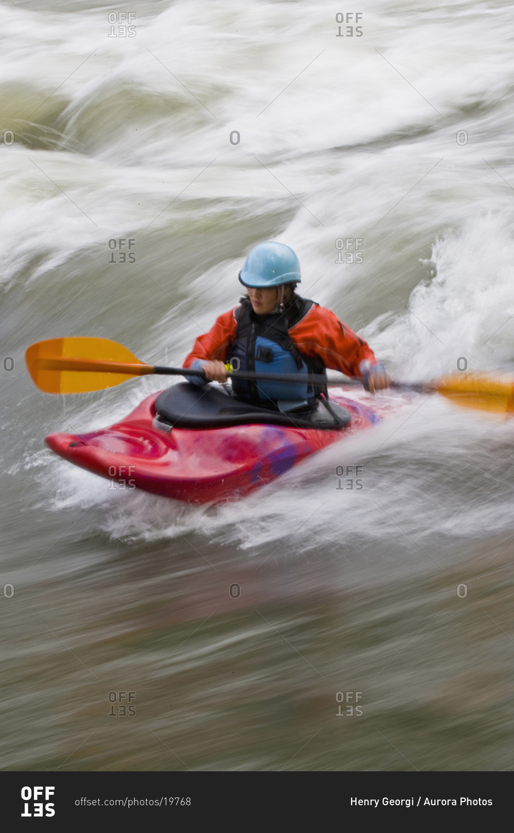 A young, Asian-looking woman surfing a wave in a whitewater kayak, Elk river, East Kootenies, British Columbia, Canada