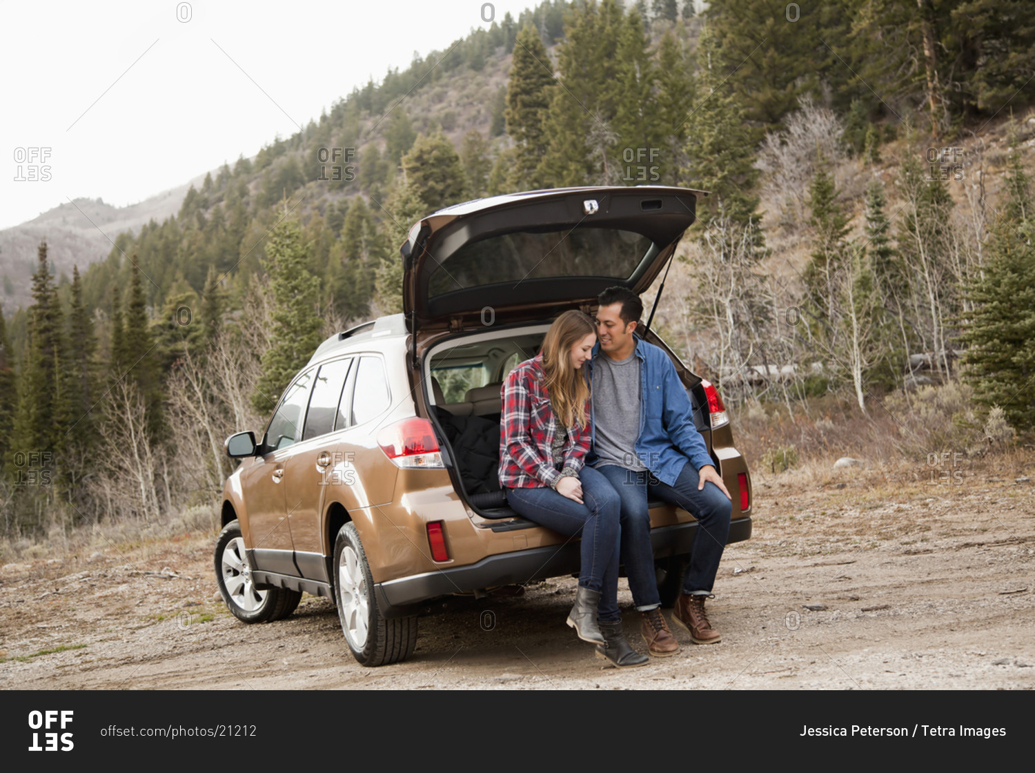 Portrait of young couple sitting in car trunk in non-urban scene