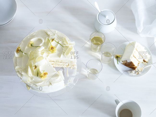 Vanilla cake decorated with white chocolate shavings and yellow pansies.