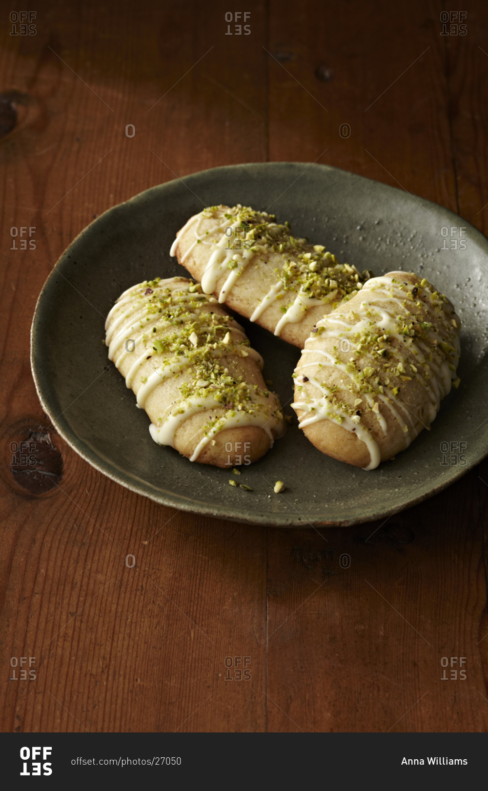 Lemon cookies topped with melted white chocolate and crushed pistachio nuts