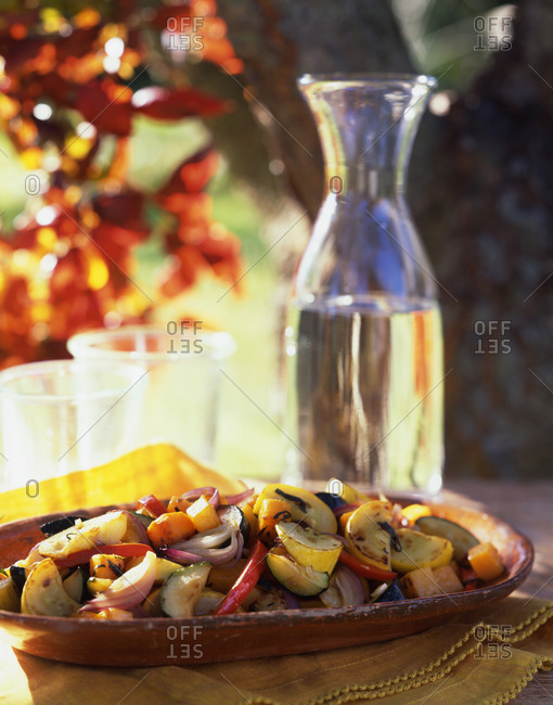 Roasted vegetables: squash, zucchini, onions, peppers and carrots with white wine on a table outside