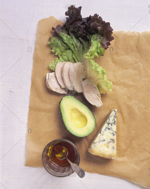 Composition with vegetables, sliced chicken breast and blue cheese displayed on textured paper