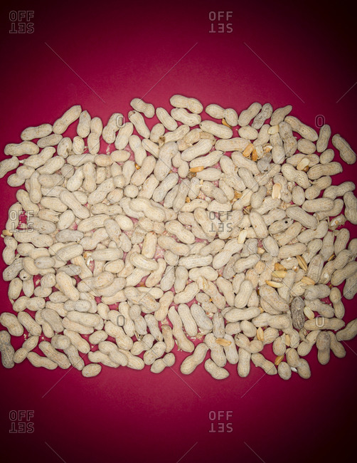 A neat piles of shelled peanuts against a red background