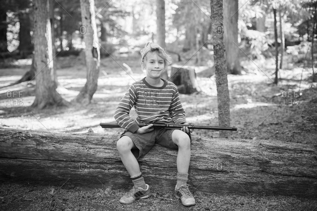 a young boy poses with a bb gun
