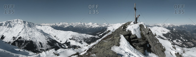 Panoramic view of snowy mountain ridges and a mountain peak with a cross