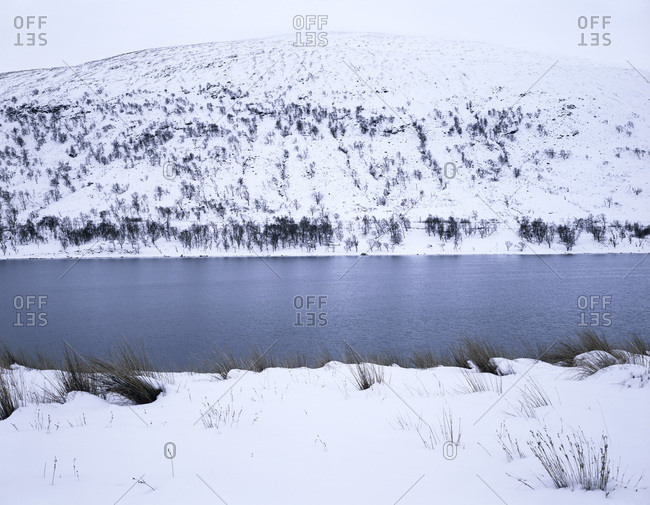 Scenic view of lake and a hill covered with snow