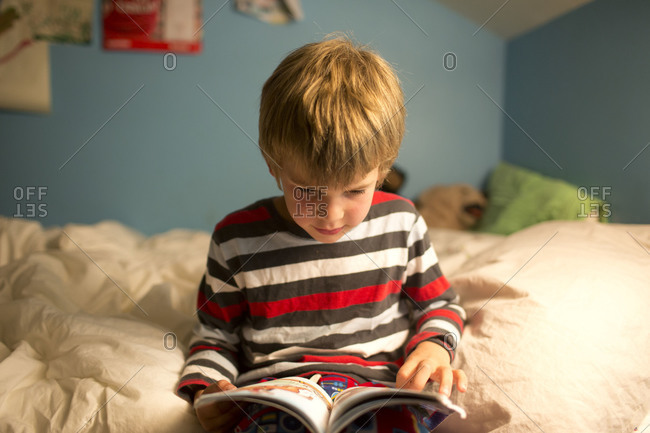 Little boy sitting on the blanket and reading.