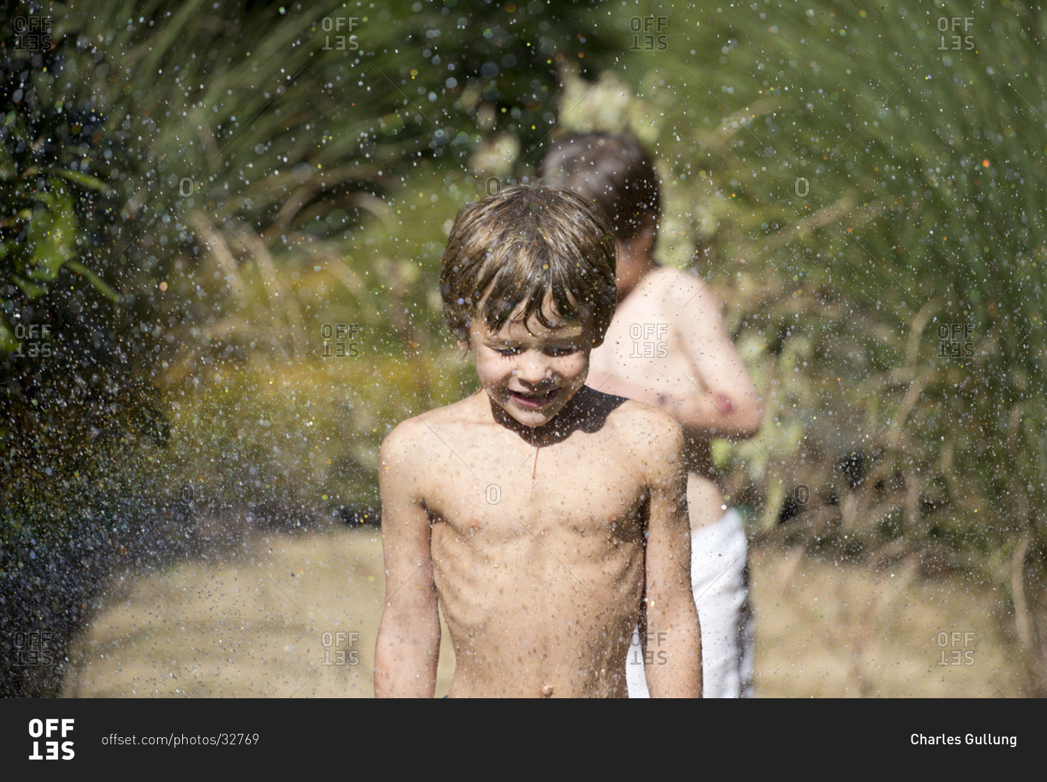 Little boys enjoying the water spraying at the backyard stock photo ...