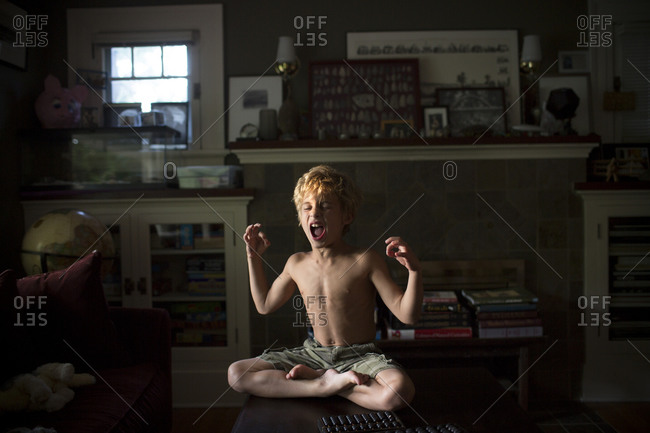 A young man with bare torso sitting in the lotus position Stock