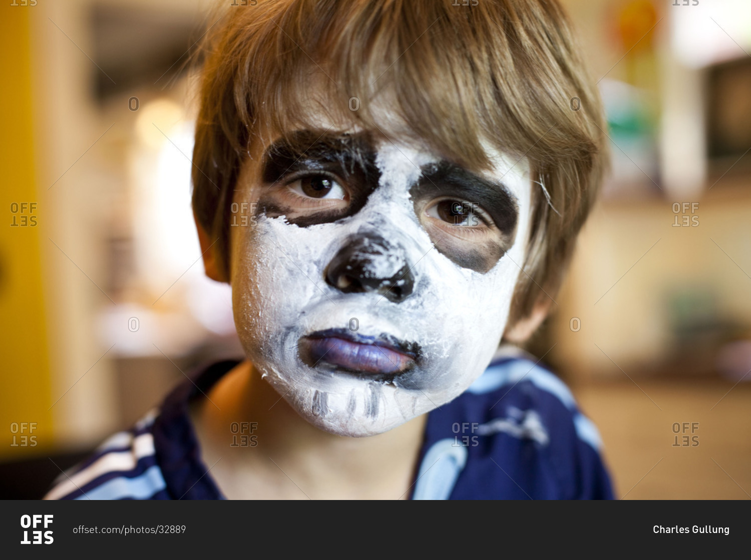 Portrait of boy with painted face and sad eyes.