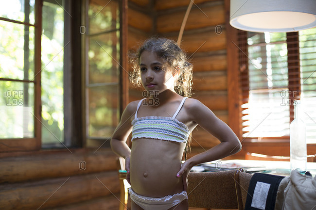 Young Caucasian girl standing akimbo in swimsuit stock photo - OFFSET