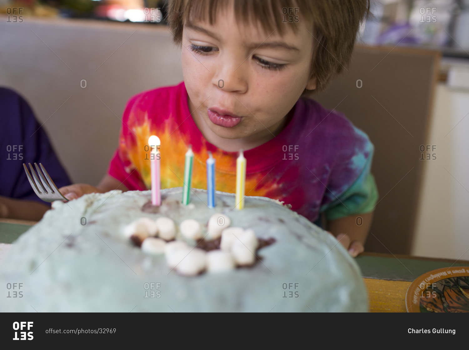 Portrait of young boy blowing out candles on his birthday cake