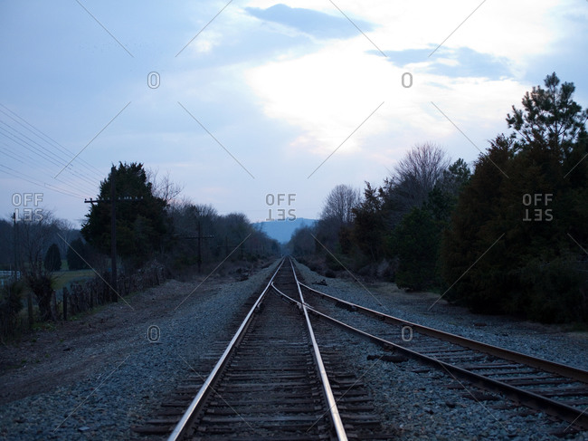 Train tracks at dusk receding in the rural countryside