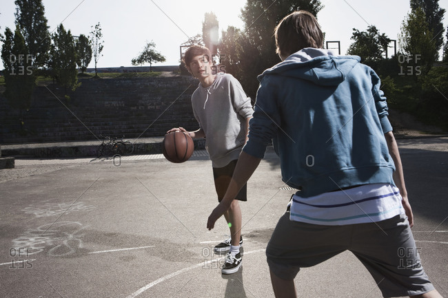 Germany, Berlin, Teenage boys playing basketball in playground