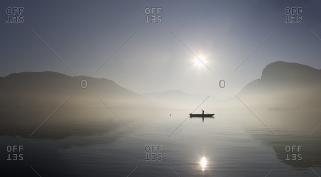 Austria, Mondsee, View of fishing boat in lake with foggy morning