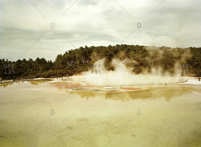 People walk around the edge of a sulfur spring