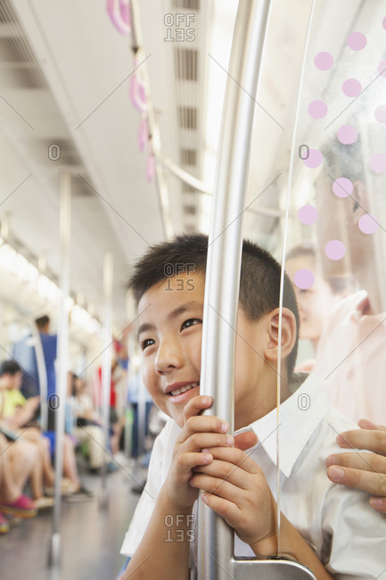 Chinese boy holding railing on subway