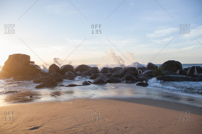 Scenic shot of waves hitting boulders on seashore