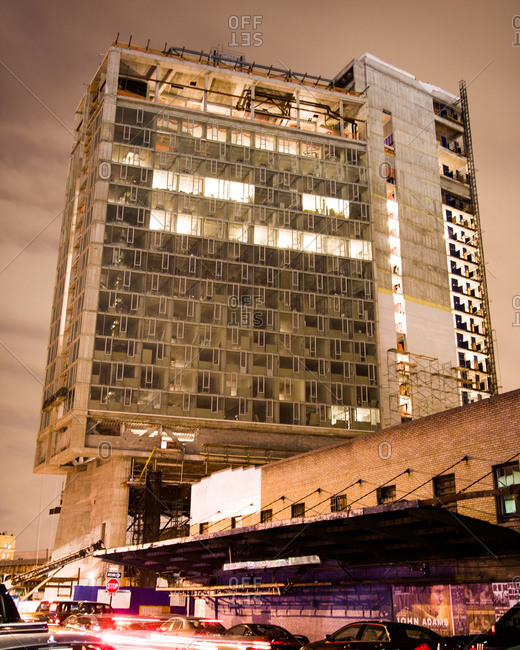 Night shot on with traffic and exterior of a tall urban building