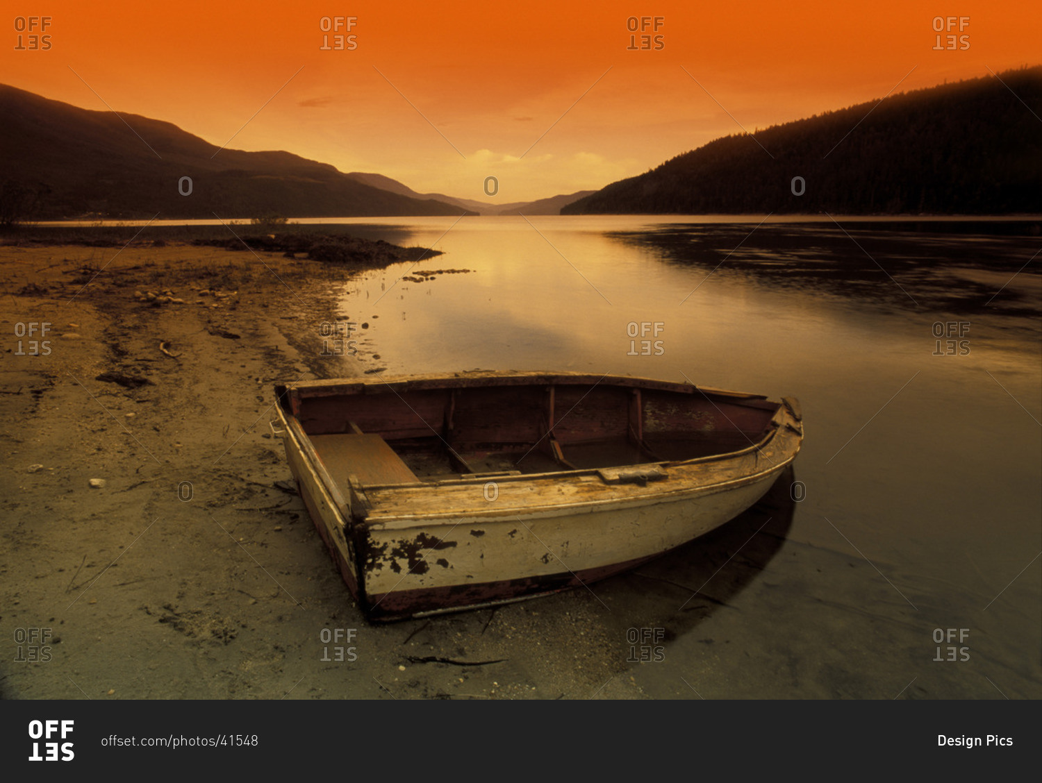 Row Boat At Water's Edge Against Sunset Backdrop