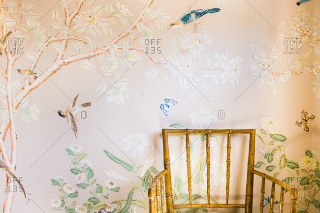 Bamboo chair displayed against floral-patterned wall