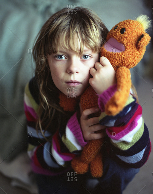 Portrait of girl cuddling soft toy monkey