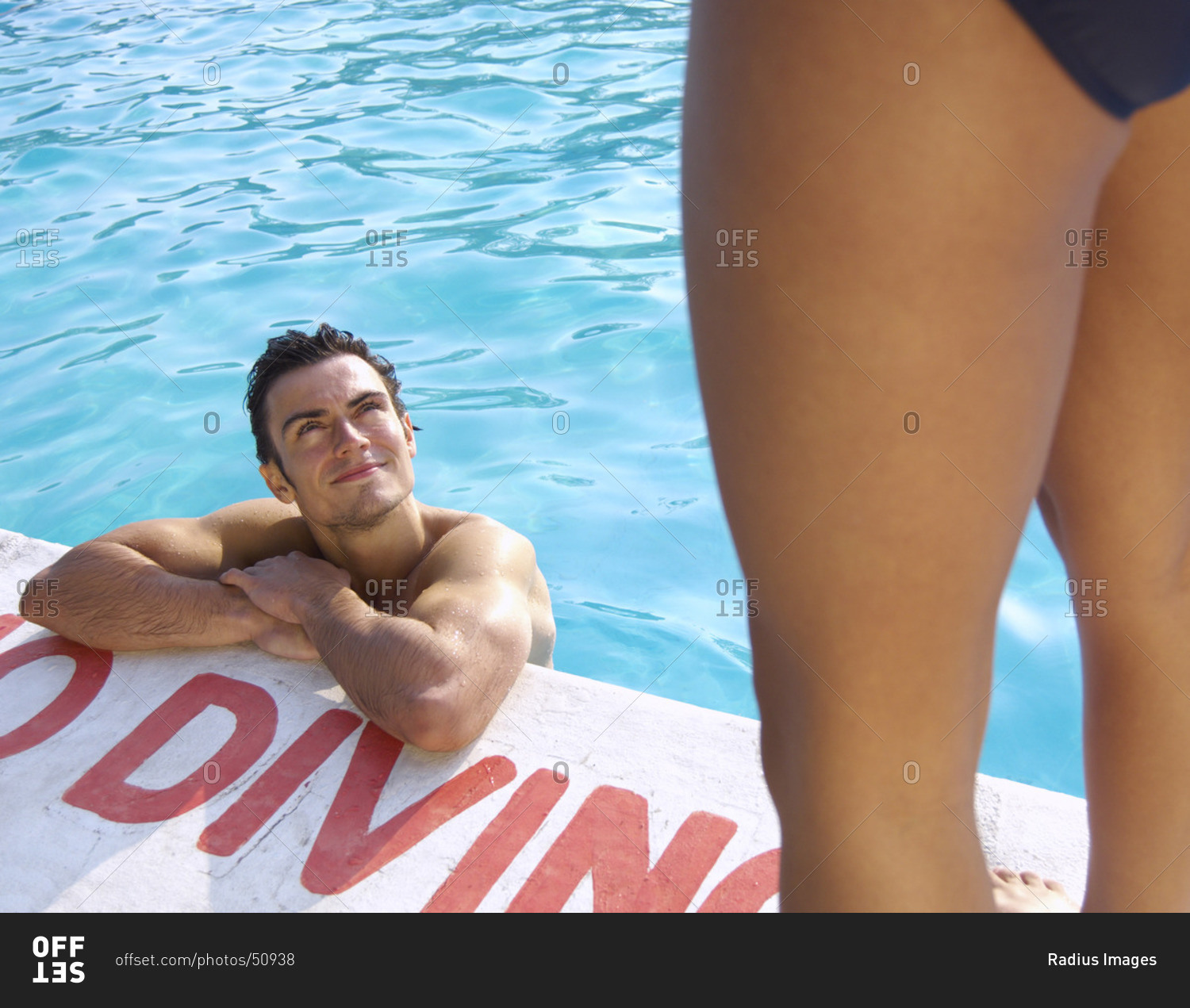 Man in swimming pool looking up at woman - Stock Image - Everypixel