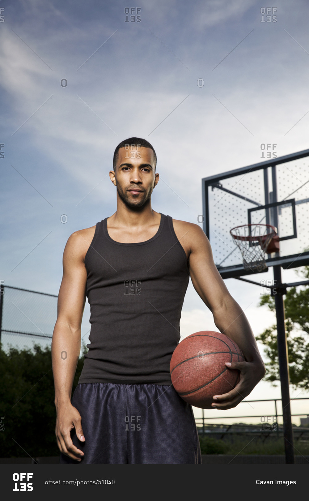 A man in a basketball uniform standing on a street photo – Free