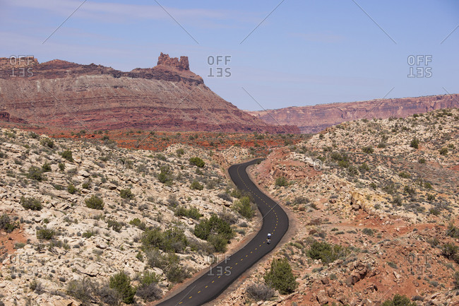 A biker rides on a pathed bike path through the desert.