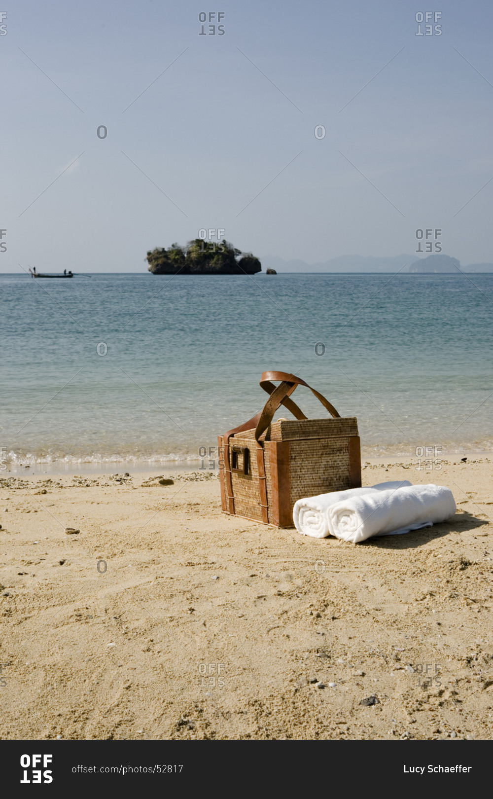 Picnic basket and rolled towels on sandy beach