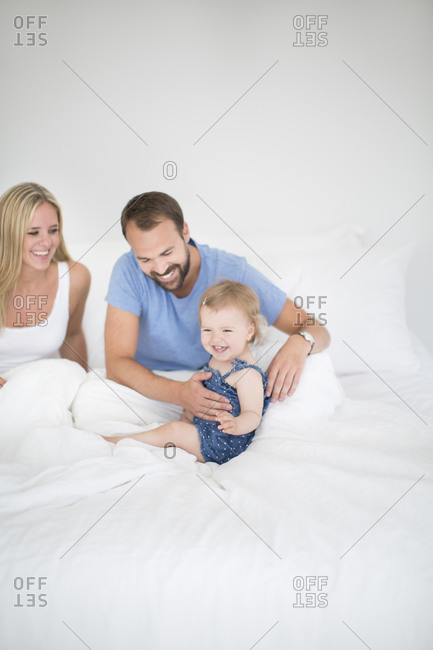 Parents with little daughter relaxing in bed