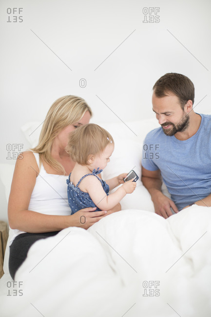 Parents with little daughter relaxing in bed